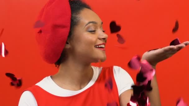赤いベレー帽を手で取って女性 代の愛ハート型の紙吹雪を落下 — ストック動画