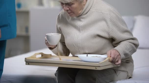 古い高齢者患者あふれている熱いお茶後トレイをクリーニング失礼な医療従事者 — ストック動画
