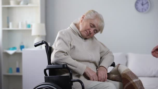 Νεαρά Νοσοκόμα Καλύπτοντας Pled Ηλικιωμένη Γυναίκα Στον Ύπνο Αναπηρική Καρέκλα — Αρχείο Βίντεο
