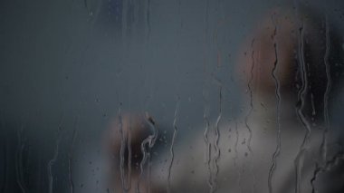 Üst düzey Bayan yalnız odada yağmurlu pencere, yaşlılık yalnızlık arkasında oturuyor ağlıyor