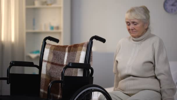 リハビリテーション センターで車椅子の近くのソファに座っている年配の女性を混乱させる — ストック動画