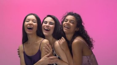 Kadınlar sarılma ve içtenlikle gülüyor, pembe bir arka plan üzerinde izole pijama