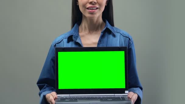 グリーン スクリーンのラップトップを保持している笑顔の女性それアプリケーション開発 — ストック動画