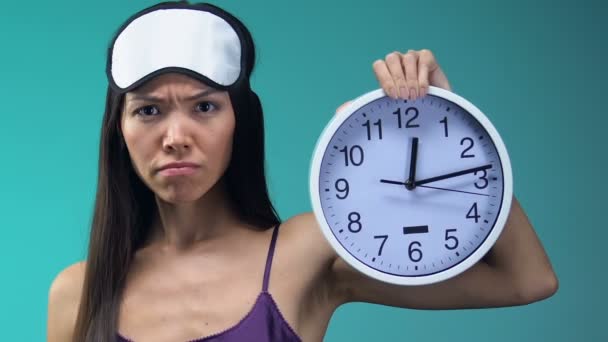 愤怒的亚洲女人穿着睡衣和眼罩在时钟时间指指点点睡觉 — 图库视频影像