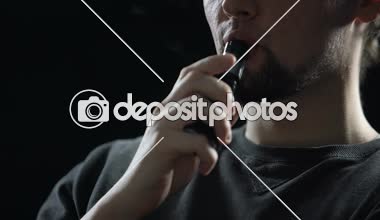Genç adam duman elektronik sigara üfleme halkaları, hipster üretimi