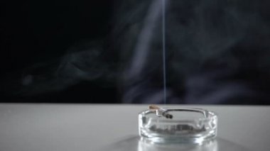 Koyu arka plan üzerinde nikotin bağımlılığı izole kül tablası yanan sigara