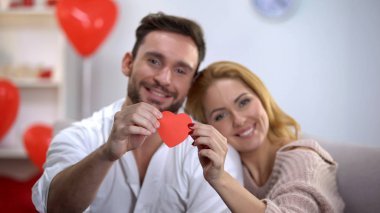 Sevgililer günü hazırlığı, gülümseyen ve kamera için kırmızı gösterilen bir çift kalp kağıt.