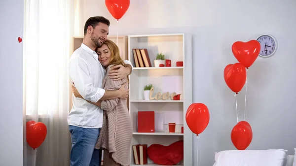 Mann Umarmt Zärtlich Ehefrau Zimmer Mit Herzförmigen Luftballons Romantisch — Stockfoto