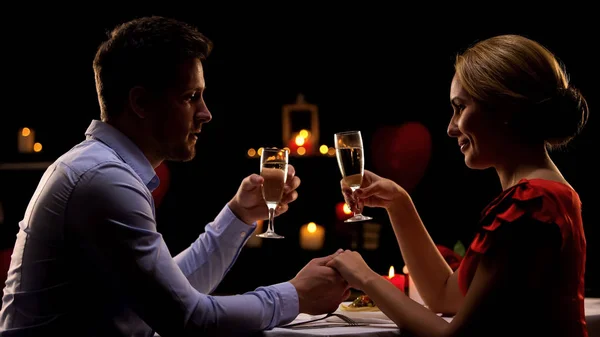 Αξιολάτρευτο Ζευγάρι Κρατώντας Χέρια Και Πίνει Σαμπάνια Κατά Ρομαντική Ημερομηνία — Φωτογραφία Αρχείου