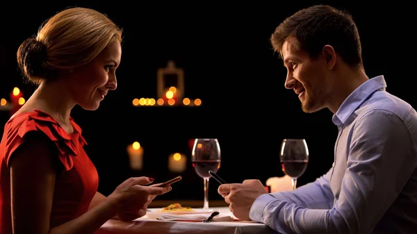 Couple in restaurant using smartphones, dating website concept, acquaintance