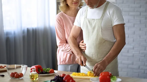 Gepensioneerde Man Koken Salade Zorg Vrouw Knuffelen Man Gezinsondersteuning Help — Stockfoto