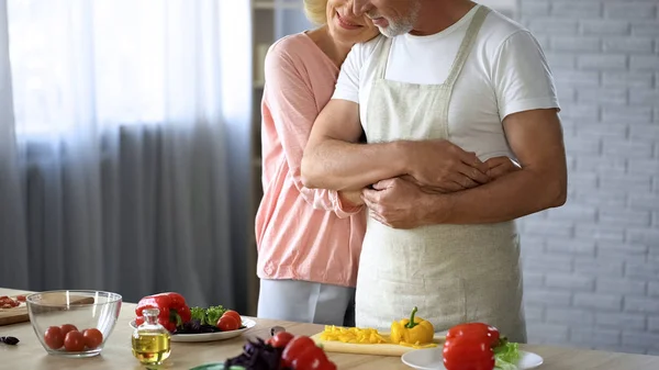 年老的女士拥抱丈夫在厨房 夫妇烹饪健康餐 家庭晚餐 — 图库照片
