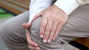 Üst düzey erkek dokunmadan diz, bankta oturan, eklem ağrısı, diz sorunları