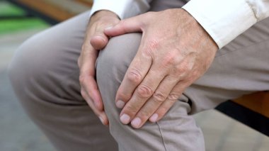 Retired man massaging knee, sitting on bench, inflammation of joints, trauma clipart