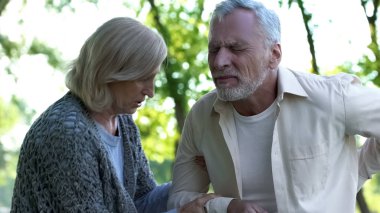 Olgun adam ona yardım park bakan karısı yürürken keskin sırt ağrısı hissediyor