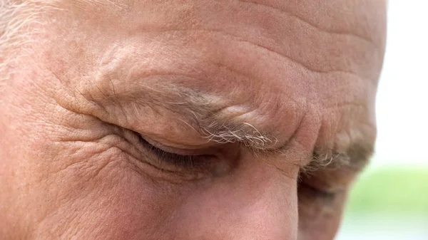 Wrinkled retired man eyes close-up, male remembering past, social security