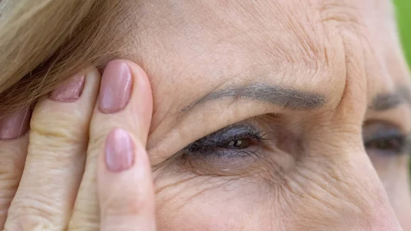 高齢者の女性がひどい片頭痛に苦しんで寺院 血圧をマッサージ — ストック写真