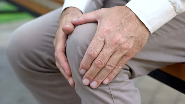 Homem Aposentado Massagear Joelho Sentado Banco Inflamação Das Articulações Trauma Imagens De Bancos De Imagens