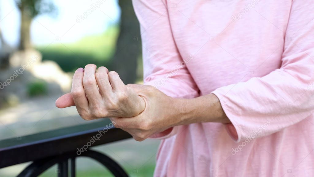 Old woman stretching numb arm, weakness of muscles in senior age, arthritis