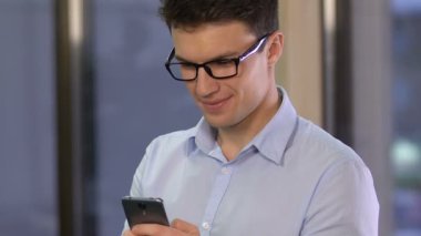 Smartphone kaydırma ve kamera için arayan genç adam memnun ile mobil uygulaması