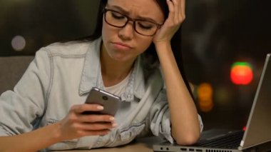 Son derece lady freelancer kaydırma telefon ve dizüstü bilgisayar, hiçbir enerji yalan yorgun