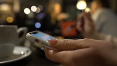 Genç kadın kahve içme ve smartphone, fotoğraflara bakarak yakın çekim