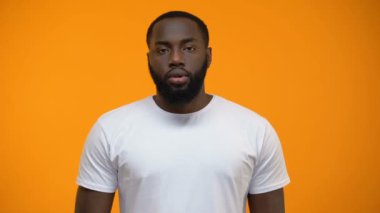Afrikalı-Amerikalı adam sessizlik jest, gösterilen gizli, sarı arka plan tutmak