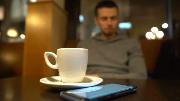 Απογοητευμένος Άνθρωπος Κάθεται Στο Καφενείο Και Ψάχνει Στο Τηλέφωνο Περιμένοντας — Αρχείο Βίντεο