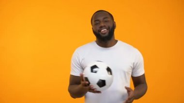 Futbol topuyla oynamaya ve başparmak işaret yukarıya gösterilen çekici Afro-Amerikan erkek