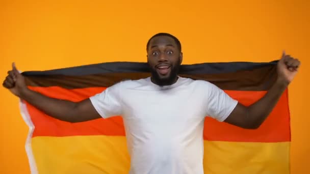 アフリカ系アメリカ人男は手を振っているドイツの旗 スポーツのファンのお気に入りのチームをサポート — ストック動画