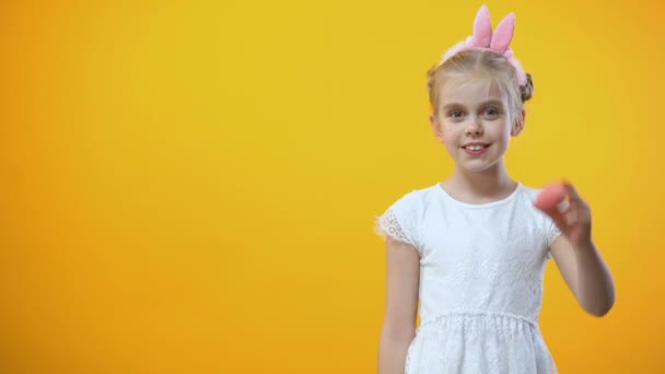 愉快的复活节题词 顽皮的女孩拿着彩色的鸡蛋在她的眼睛前面 — 图库视频影像