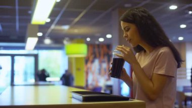 Genç erkek kafeterya masada oturan ve kameraya gülümseyen meşrubat zevk