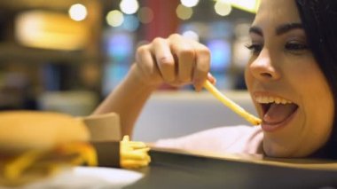 Yeme heyecanlı genç kadın Fransız patates kızartması, abur cubur zevk, yemek