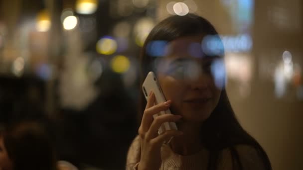美丽的年轻微笑的女人在电话聊天和等待的朋友在舒适的咖啡馆 — 图库视频影像