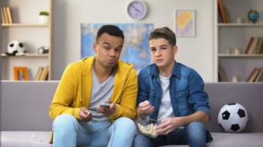 Çok ırklı erkek genç arkadaşlar futbol tartışırken yeme patlamış mısır, boş zaman maç