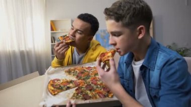 Afrikalı-Amerikalı ve Avrupalı genç arkadaş pizza, zevk sağlıksız gıda