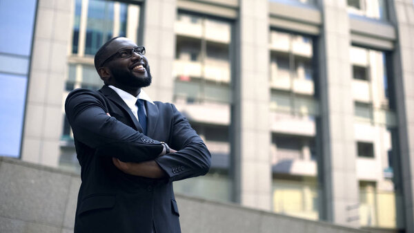 Successful architect crossed arms looking up at finished building, professional