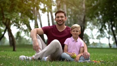 Baba ve oğul parkta oturan tutan yeşil elma, vejetaryen aile, sağlık