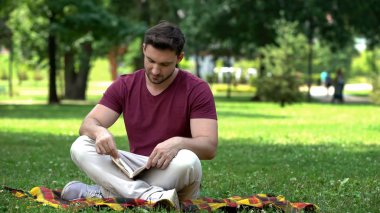 Yakışıklı erkek parkta oturan ilginç macera kitap okuma en çok satanlar