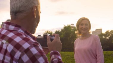 Yaşlı adam onun çekici karısı fotoğrafını parkta çekmek günbatımı, Tarih, hobi