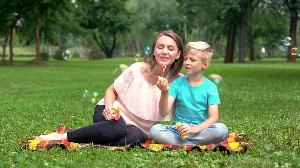 Šťastný Kluk Vyfukuje Bubliny Matka Synem Parku Šťastné Společné Dovolené — Stock fotografie