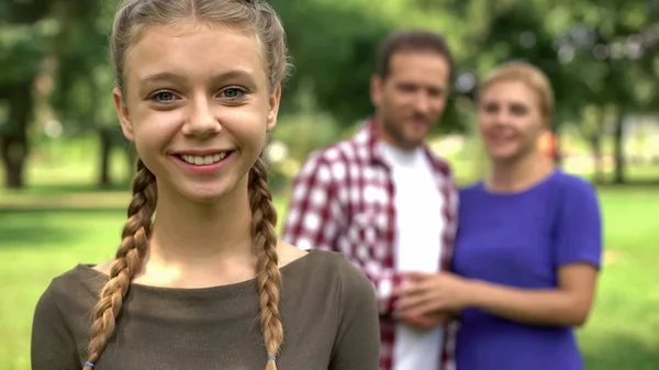 美丽的少女微笑在她幸福的父母的背景下 关心家庭 — 图库照片