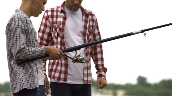 父は魚 釣り竿をキャスト 装置を使用する彼の 代の息子を教える — ストック写真
