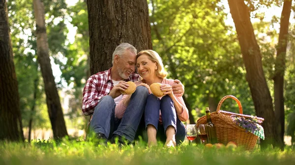 Fröhliches Altes Paar Das Sich Auf Gras Ausruht Und Burger — Stockfoto