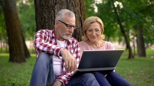 Grootouders Rusten Park Kijken Naar Interessante Video Laptop App — Stockfoto