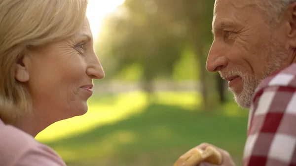 Pareja Mayor Sonriendo Disfrutando Picnic Parque Hombre Sosteniendo Hamburguesa Comida —  Fotos de Stock