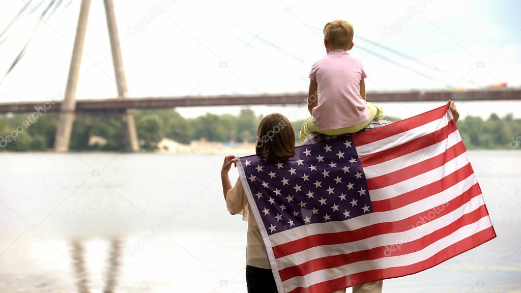 Family wrapped in American flag looking at bridge, immigration for better life