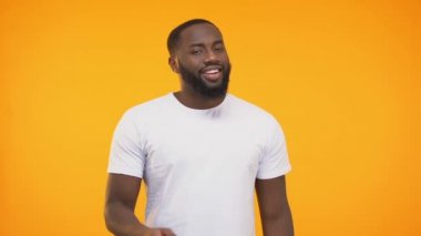 İşaret parmağını bilerek sarı arka plana karşı kendini beğenmiş Afro-Amerikan adam