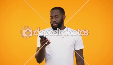 Şaşırdım ve hayret siyah adam onun smartphone sarı arka plana karşı tarama
