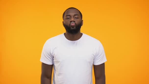 若い黒人男性空気キスを送信して 黄色の背景に対してカメラのまばたき — ストック動画
